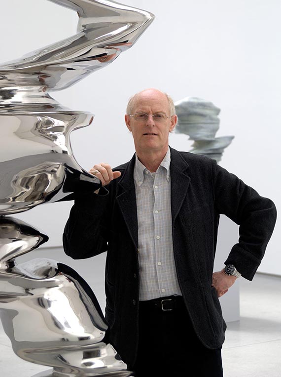 Illustration  for: Tony Cragg in front of another stainless steel sculpture. © VG Bild-Kunst, Bonn 2025